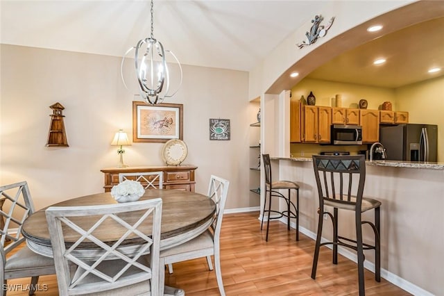 dining area with sink, an inviting chandelier, and light hardwood / wood-style flooring