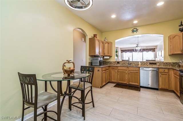 kitchen featuring pendant lighting, sink, stainless steel dishwasher, and dark stone counters