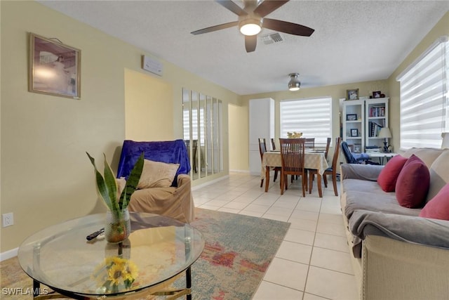 tiled living room with ceiling fan, a wealth of natural light, and a textured ceiling