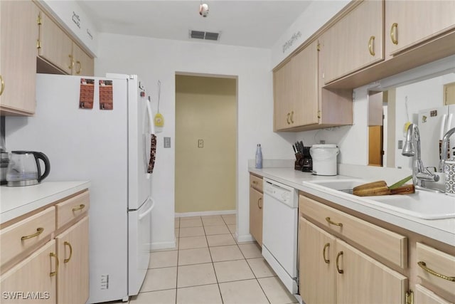 kitchen with light brown cabinetry, sink, white appliances, and light tile patterned flooring