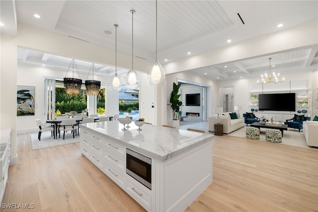 kitchen with pendant lighting, stainless steel microwave, white cabinetry, and an inviting chandelier