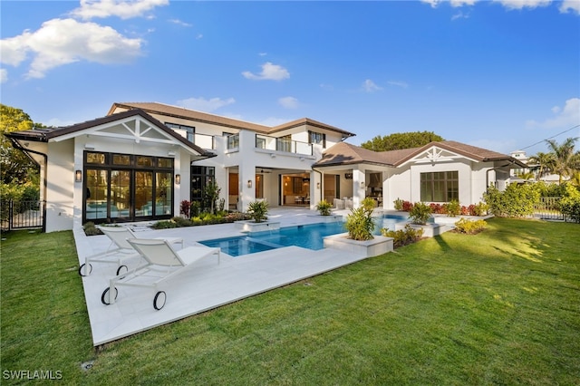 rear view of property with a fenced in pool, a lawn, and a patio