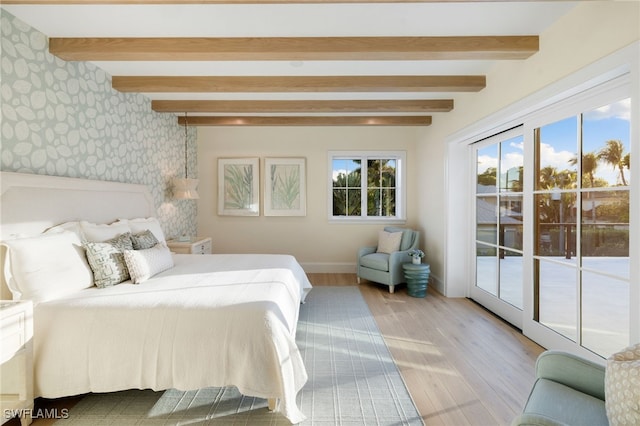 bedroom featuring access to exterior, beam ceiling, and light hardwood / wood-style flooring