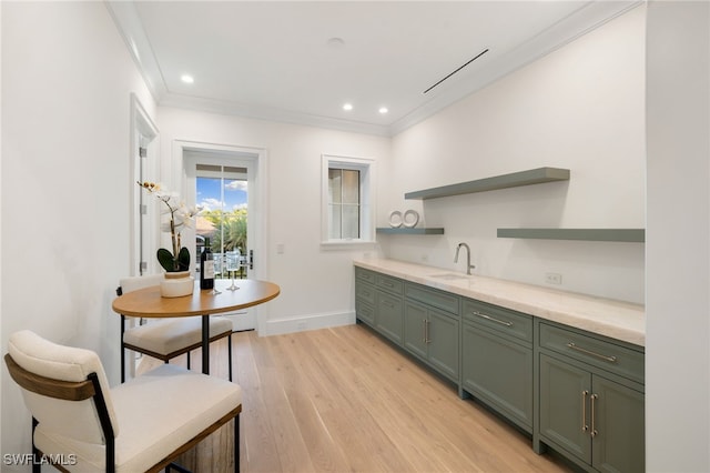 kitchen featuring sink, crown molding, green cabinets, and light wood-type flooring