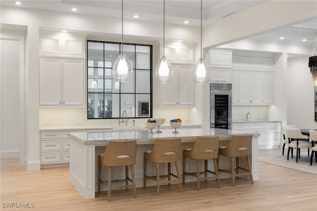 kitchen featuring stainless steel refrigerator, white cabinetry, and a large island with sink