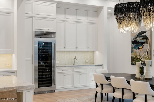 interior space featuring wine cooler, light stone counters, and white cabinets