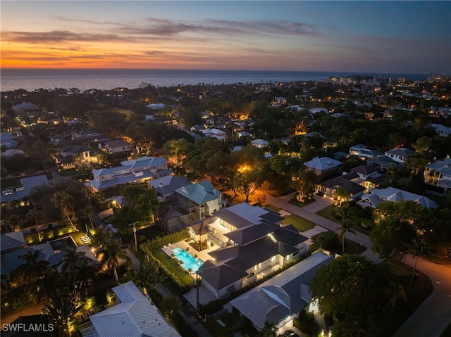 aerial view at dusk featuring a water view