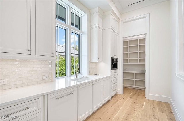 460 2nd Ave N, Naples, FL 34102 - kitchen featuring a sink, light wood-style flooring, white cabinetry, backsplash, and light countertops