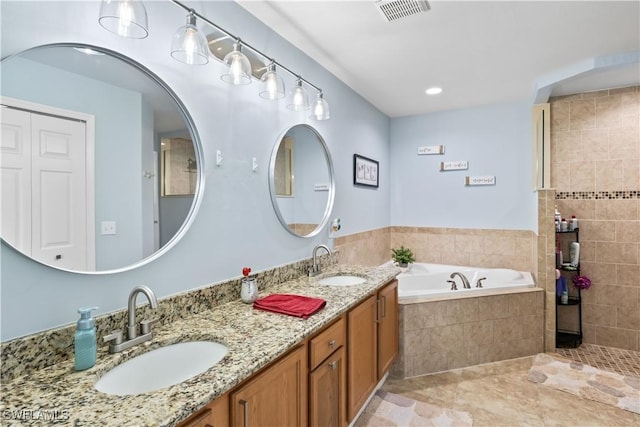 bathroom featuring vanity, tile patterned flooring, and tiled tub