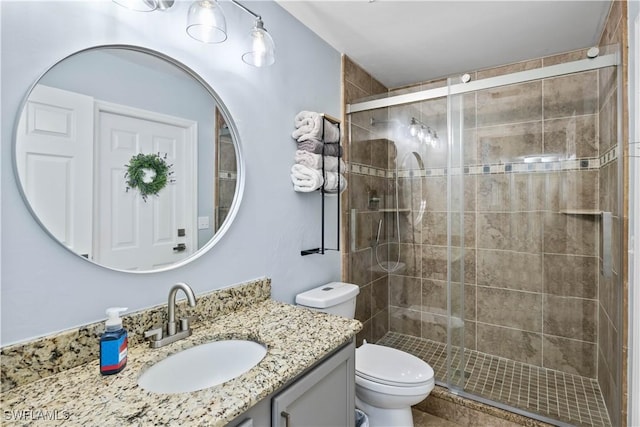 bathroom with vanity, toilet, and a shower with door