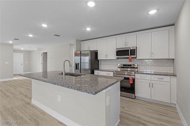 kitchen featuring white cabinets, sink, stainless steel appliances, and a center island with sink