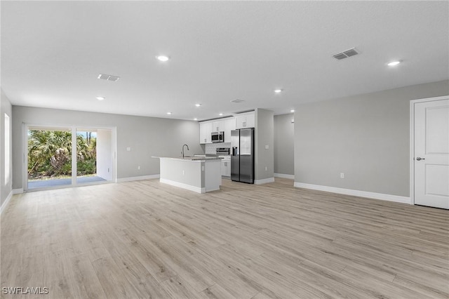 337 Woodburn Dr, Lehigh Acres, FL 33972 - unfurnished living room featuring baseboards, recessed lighting, light wood-style flooring, and a sink
