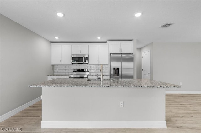 337 Woodburn Dr, Lehigh Acres, FL 33972 - kitchen featuring stainless steel appliances, a sink, a center island with sink, baseboards, and white cabinets