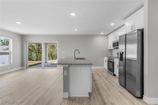 337 Woodburn Dr, Lehigh Acres, FL 33972 - kitchen with appliances with stainless steel finishes, a sink, a kitchen island with sink, stone counters, and light wood-type flooring