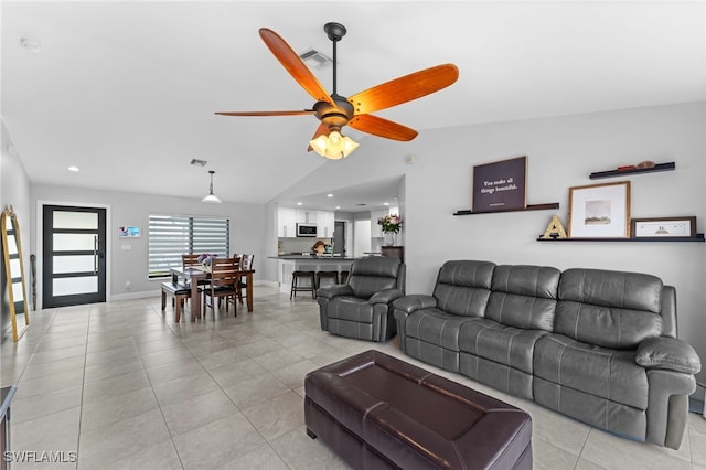 tiled living room with ceiling fan and lofted ceiling