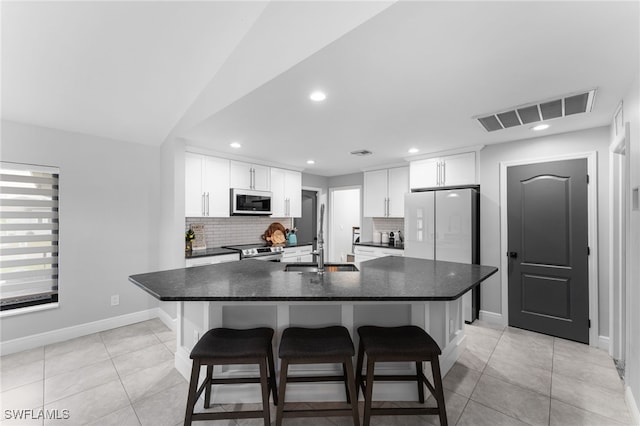 kitchen featuring a kitchen breakfast bar, white appliances, white cabinetry, and an island with sink