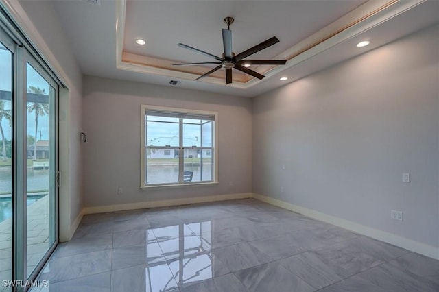 spare room with ceiling fan and a tray ceiling