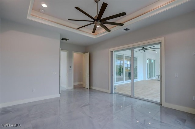 spare room featuring a tray ceiling and ceiling fan