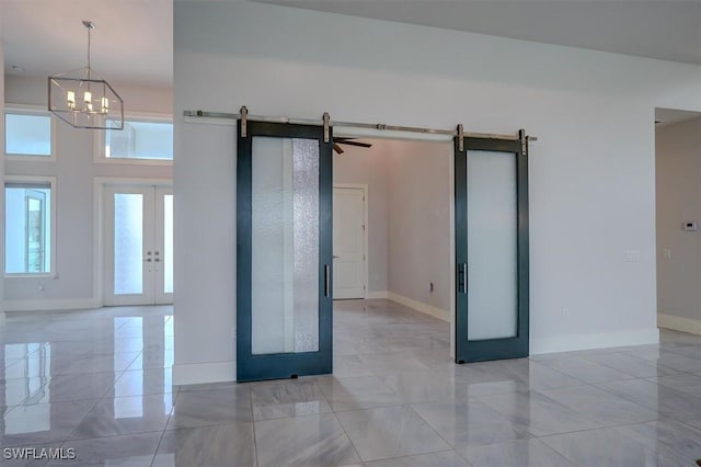 unfurnished room featuring a towering ceiling, french doors, and a barn door