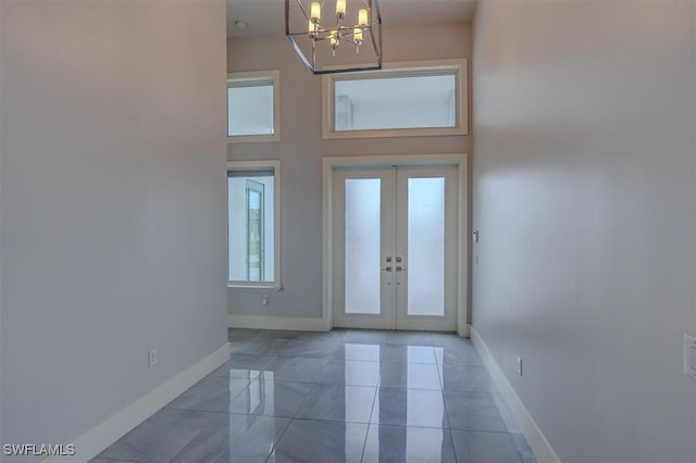 entryway with a towering ceiling, a notable chandelier, and french doors