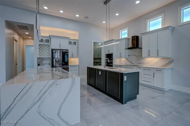 kitchen featuring wall chimney exhaust hood, tasteful backsplash, decorative light fixtures, a center island with sink, and black appliances