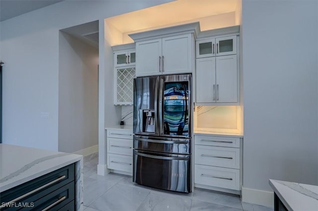 kitchen featuring light stone counters and fridge with ice dispenser