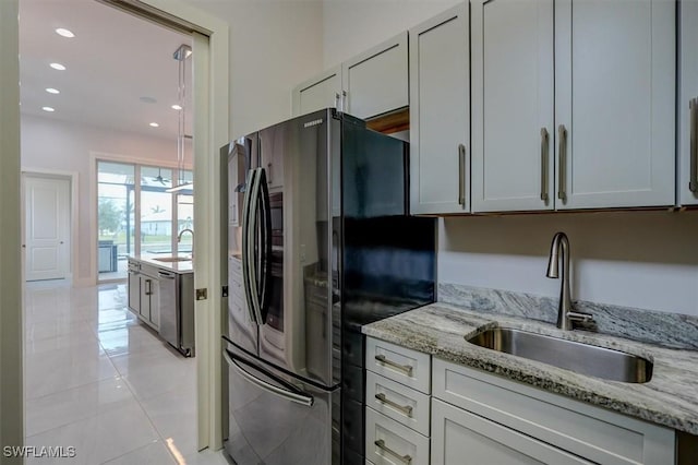 kitchen featuring sink, light tile patterned floors, dishwasher, light stone counters, and black fridge