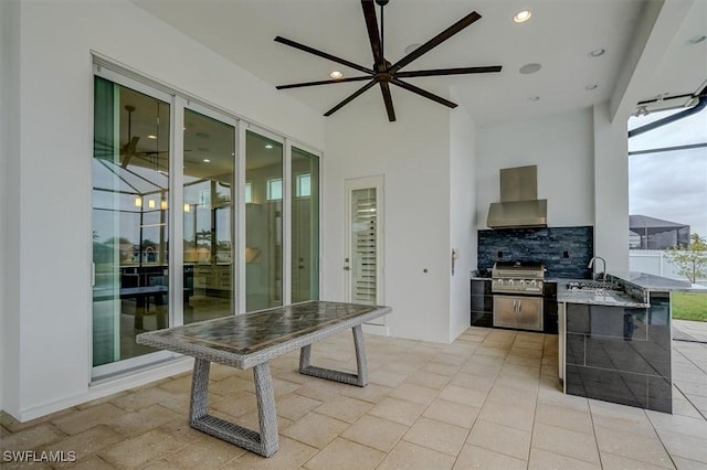 exterior space featuring light stone counters, wall chimney exhaust hood, sink, and decorative backsplash