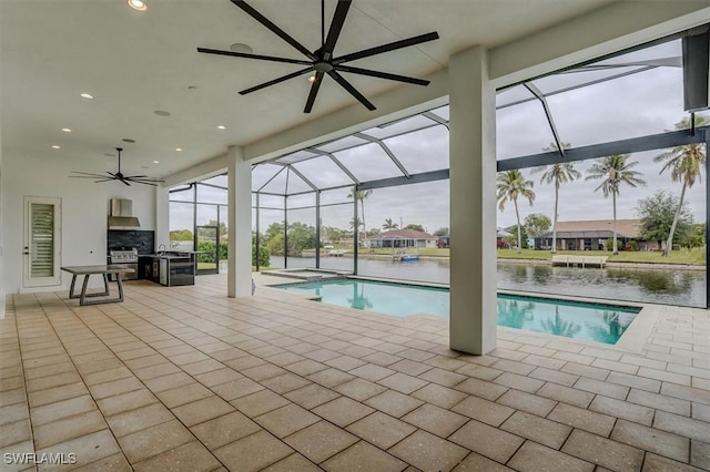 view of pool with a water view, a patio, and an outdoor kitchen