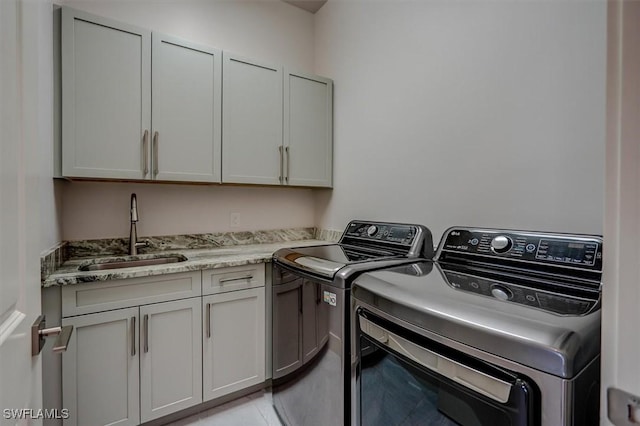 laundry area featuring cabinets, washer and clothes dryer, and sink