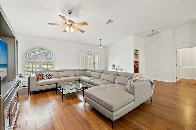 living room with ceiling fan, dark hardwood / wood-style floors, washer / dryer, and lofted ceiling