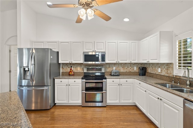 kitchen with vaulted ceiling, appliances with stainless steel finishes, and white cabinets