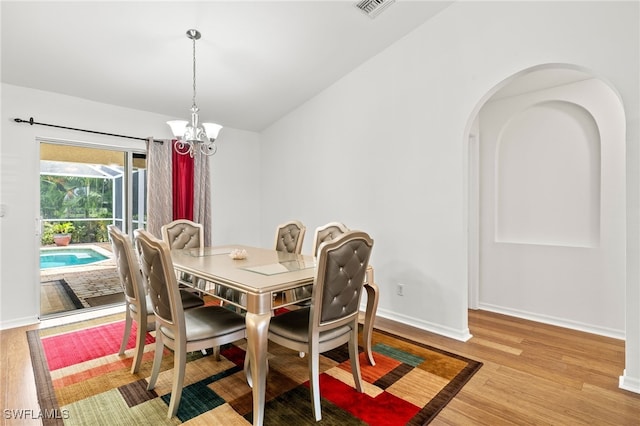 dining area with light hardwood / wood-style flooring and an inviting chandelier