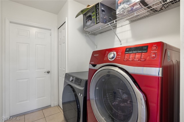 washroom with light tile patterned floors and washer and clothes dryer