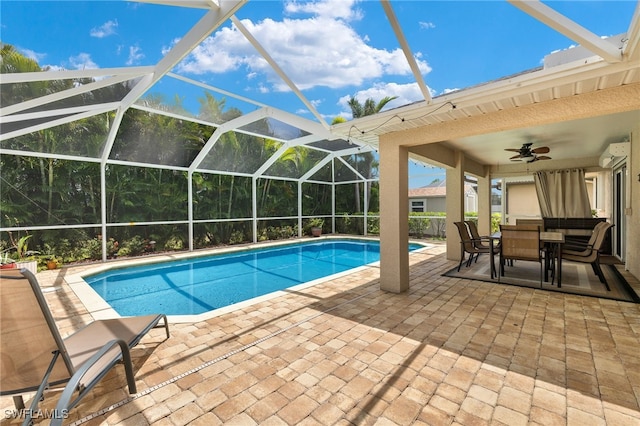 view of swimming pool with glass enclosure, ceiling fan, and a patio