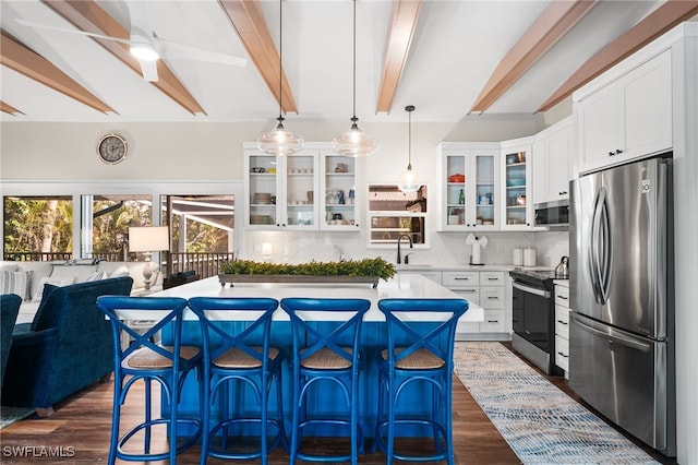 kitchen featuring pendant lighting, a kitchen island, sink, stainless steel appliances, and white cabinets