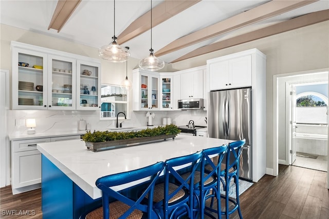 kitchen featuring decorative light fixtures, white cabinets, stainless steel appliances, and a center island