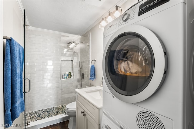 bathroom with washer / dryer, toilet, walk in shower, crown molding, and vanity