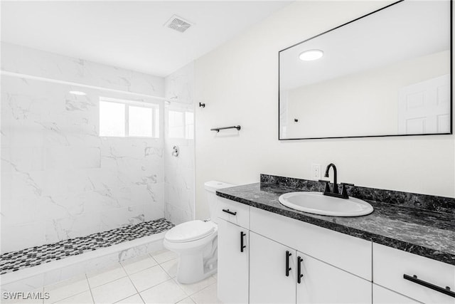 bathroom with tiled shower, vanity, toilet, and tile patterned flooring