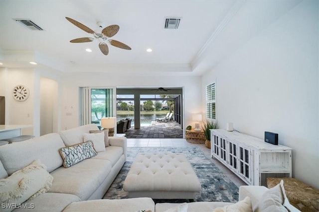 living room with ceiling fan, a tray ceiling, ornamental molding, and a healthy amount of sunlight