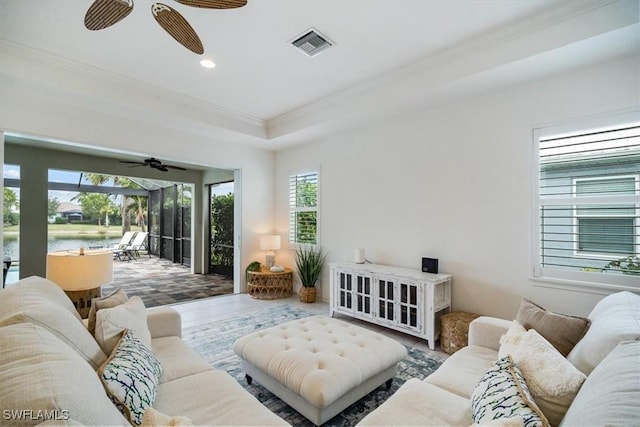 living room with a raised ceiling, tile patterned flooring, ornamental molding, and ceiling fan