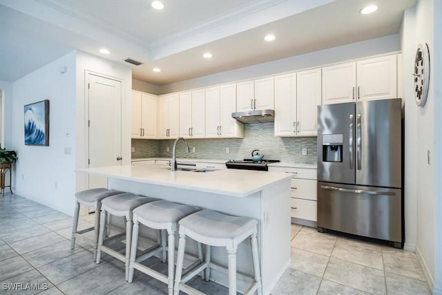 kitchen featuring white cabinetry, stainless steel fridge with ice dispenser, a breakfast bar area, and an island with sink