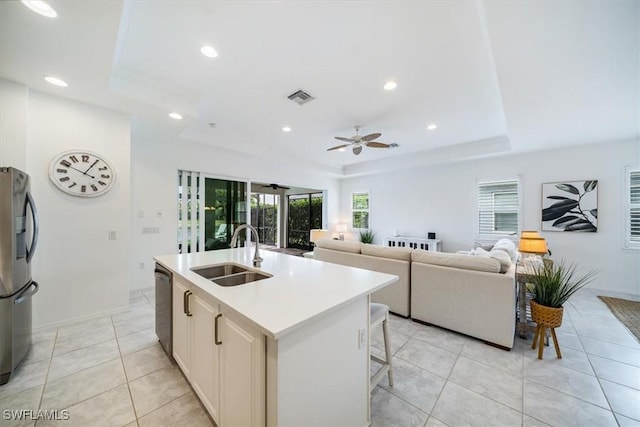 kitchen featuring appliances with stainless steel finishes, sink, a raised ceiling, a center island with sink, and a breakfast bar area