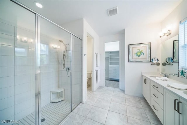 bathroom with tile patterned floors, toilet, vanity, and walk in shower