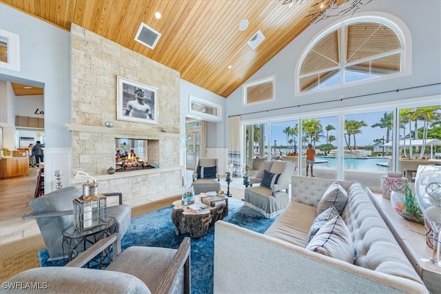 living room featuring wood ceiling, a fireplace, and high vaulted ceiling