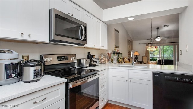 kitchen with white cabinetry, kitchen peninsula, appliances with stainless steel finishes, light stone counters, and sink