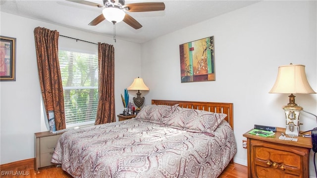 bedroom with ceiling fan, multiple windows, and light hardwood / wood-style floors