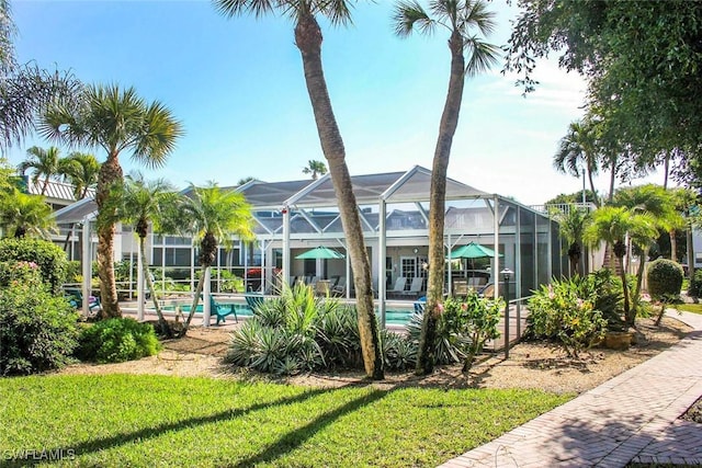 back of house with a lanai and a lawn