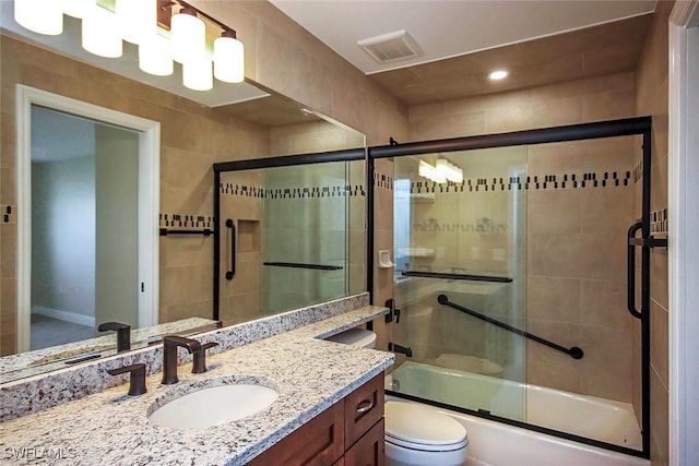 full bathroom featuring toilet, vanity, and shower / bath combination with glass door