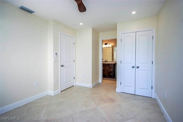 unfurnished bedroom with ceiling fan, light tile patterned floors, ensuite bathroom, and a closet